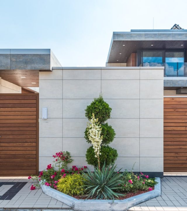 Contemporary house exterior featuring a stylish wooden facade, entrance gate, and vibrant garden.
